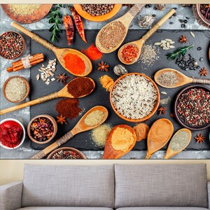May include: A flat lay image of various spices and grains in bowls and spoons on a dark gray surface. The spices include black peppercorns, red pepper flakes, cumin, and coriander. The grains include rice and quinoa. The spoons are wooden and have a natural finish.