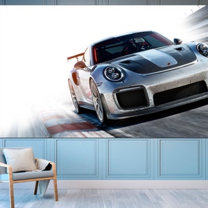 May include: A silver Porsche 911 GT3 RS race car speeding on a track with a blurred background.