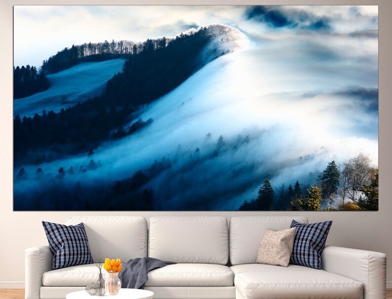 May include: A panoramic view of a misty forest with rolling hills and a blue sky. The fog is thick and white, and the trees are dark green. The image is taken from a high vantage point, looking down on the forest.