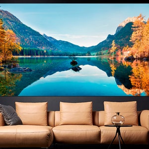 May include: A scenic landscape photograph featuring a lake surrounded by mountains and trees. The lake is reflecting the mountains and trees, creating a mirror-like effect. The trees are in autumn colors, with shades of yellow, orange, and red.