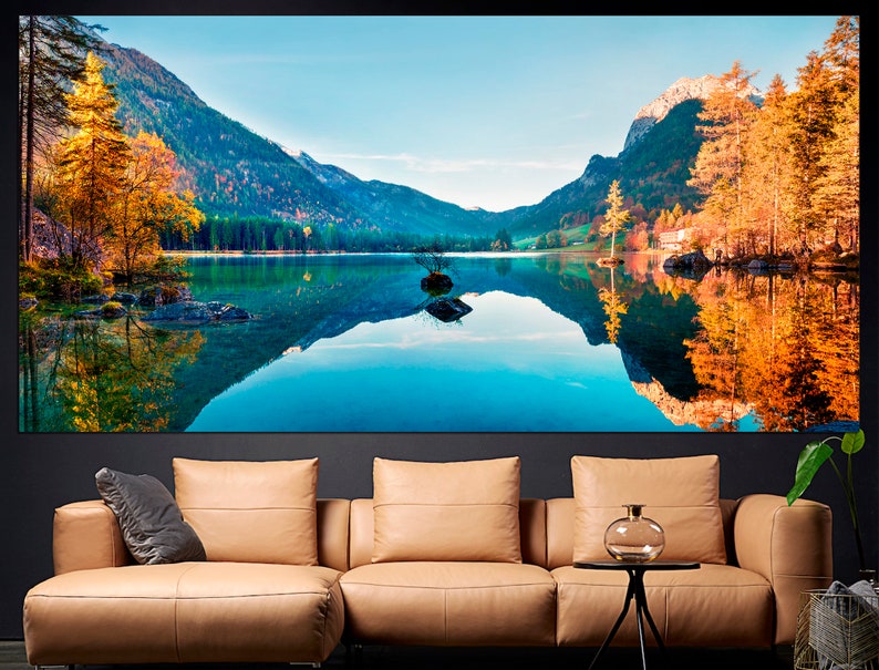 May include: A scenic landscape photograph featuring a lake surrounded by mountains and trees. The lake is reflecting the mountains and trees, creating a mirror-like effect. The trees are in autumn colors, with shades of yellow, orange, and red.