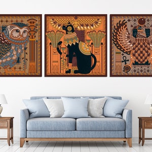 May include: Three framed prints with an Egyptian theme. The first print features an owl with intricate details, the second print features a black cat with a golden collar, and the third print features a winged creature with a golden crown.