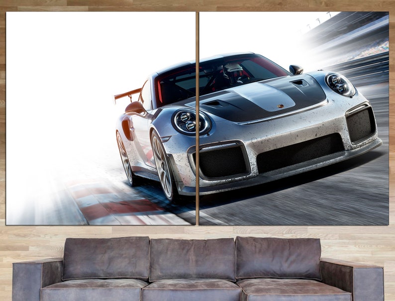 May include: A silver and black sports car speeding on a race track. The car has a black stripe down the hood and a large wing on the back.