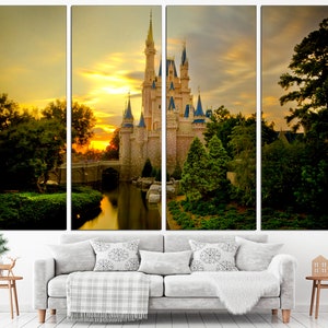 May include: A multi-panel canvas print depicting a fairytale castle with a moat and lush greenery, bathed in the golden light of a sunset. The castle is a light brown colour with blue accents and towers. The sky is a vibrant orange and yellow with fluffy white clouds.