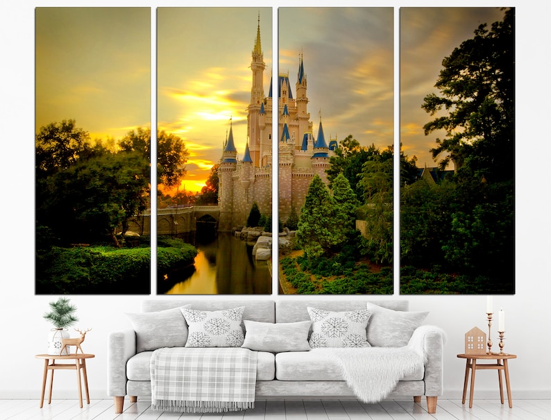 May include: A multi-panel canvas print depicting a fairytale castle with a moat and lush greenery, bathed in the golden light of a sunset. The castle is a light brown colour with blue accents and towers. The sky is a vibrant orange and yellow with fluffy white clouds.