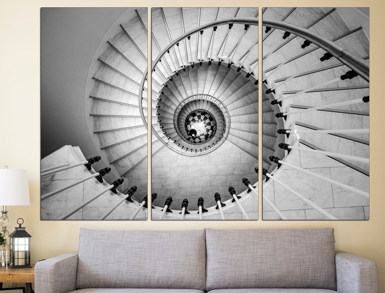 May include: A black and white photograph of a spiral staircase. The staircase is made of white marble and has a black metal railing. The photo is split into three sections, showing the staircase from different angles.