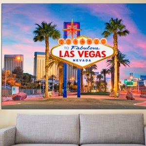 May include: A canvas print of the iconic Welcome to Fabulous Las Vegas sign at dusk. The sign is white with a gold border and features the text "Welcome to Fabulous Las Vegas Nevada". Palm trees and city buildings are in the background.