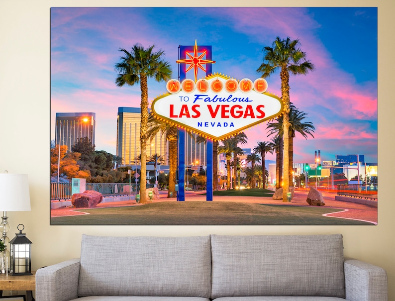 May include: A canvas print of the iconic Welcome to Fabulous Las Vegas sign at dusk. The sign is white with a gold border and features the text "Welcome to Fabulous Las Vegas Nevada". Palm trees and city buildings are in the background.