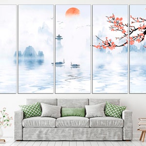 May include: A multi-panel canvas print depicting a serene landscape with misty mountains, a calm lake, and a traditional Chinese building. The scene is painted in soft blue and white tones, with a touch of orange for the rising sun. A delicate branch of pink blossoms adds a touch of color to the composition.