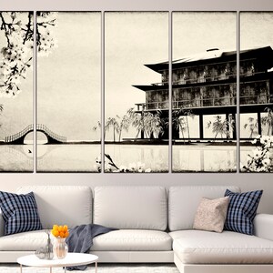 May include: A black and white canvas print of a traditional Japanese house with a bridge and cherry blossoms. The house is on stilts over a body of water. The print is in a vintage style.