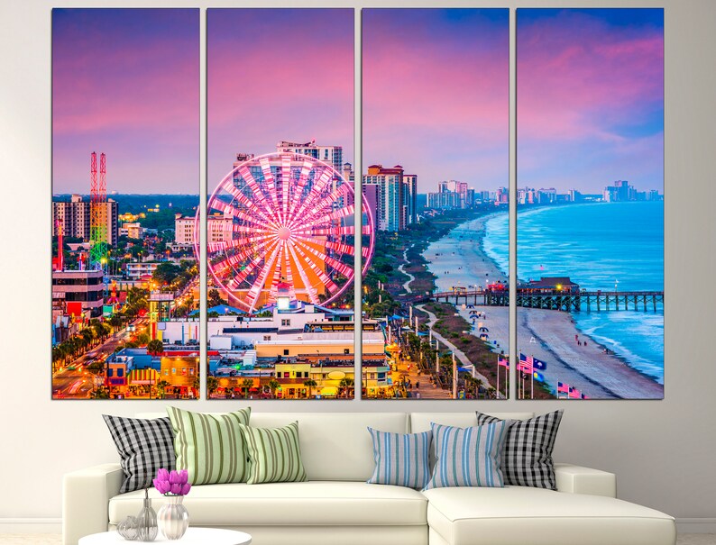 May include: A panoramic view of a city skyline with a Ferris wheel in the foreground. The city is located on a beach with a pier extending into the ocean. The sky is a vibrant pink and purple.