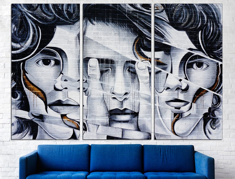 May include: A triptych of three black and white portraits of people with their faces partially obscured by geometric shapes. The portraits are painted on a white brick wall background.