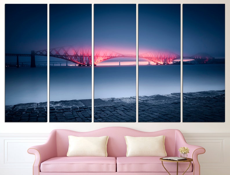 May include: A five-panel canvas print of a bridge lit up in pink and red at night. The bridge is over a body of water and there is a stone walkway in the foreground.