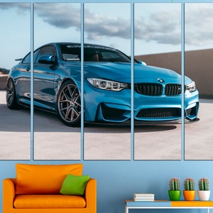 May include: A blue BMW M4 sports car parked on a concrete surface. The car has black wheels and a black grille. The car is in focus, and the background is blurred.