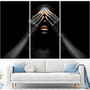 May include: A black and white portrait of a person with gold makeup on their lips and eyelids. The person is covering their eyes with their hands.