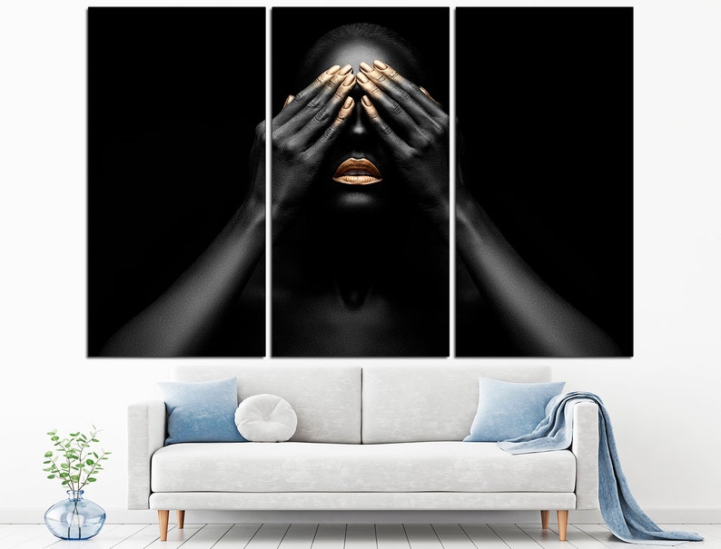 May include: A black and white portrait of a person with gold makeup on their lips and eyelids. The person is covering their eyes with their hands.