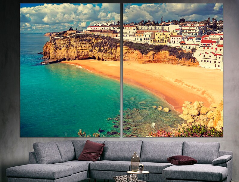 May include: A panoramic view of a coastal town with white buildings perched on a cliff overlooking a sandy beach and turquoise water.