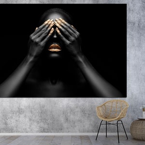 May include: A person with black skin and gold painted lips and fingernails covers their eyes with their hands. The background is black.