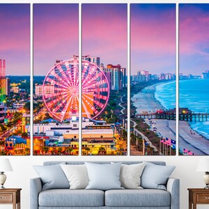 May include: A panoramic view of Myrtle Beach, South Carolina at sunset. The image features a Ferris wheel, a pier, a beach, and the city skyline. The sky is a vibrant pink and orange, and the water is a deep blue.