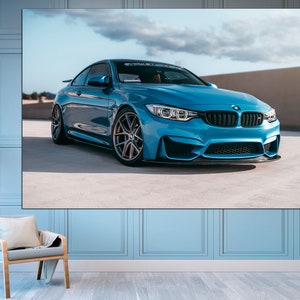 May include: A blue BMW M4 sports car parked on a concrete surface. The car has black wheels and a black front splitter.