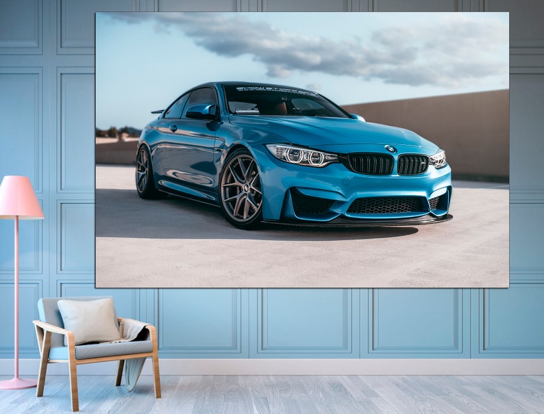 May include: A blue BMW M4 sports car parked on a concrete surface. The car has black wheels and a black front splitter.