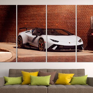 May include: A white Lamborghini Aventador SVJ Roadster parked in front of a brick wall. The car has black accents and gold wheels.