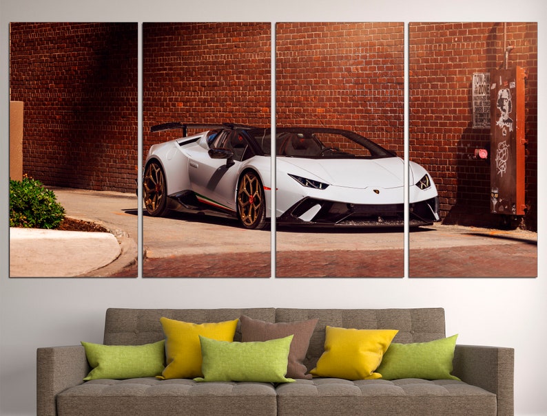 May include: A white Lamborghini Aventador SVJ Roadster parked in front of a brick wall. The car has black accents and gold wheels.