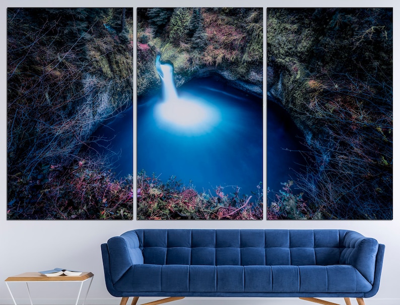 May include: A tri-panel canvas print featuring a waterfall cascading into a deep blue pool surrounded by lush greenery. The image is taken from a high angle, giving a dramatic perspective of the natural scene.