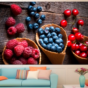 May include: A rustic wooden background with three waffle cones filled with fresh fruit. The cones are filled with blueberries, raspberries, and cherries.