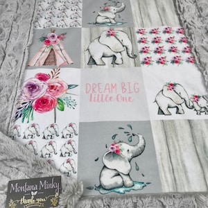 May include: A gray and white baby blanket with a patchwork design featuring elephants, flowers, and a teepee. The blanket has a gray minky backing and the text "Dream Big Little One" is printed in pink.