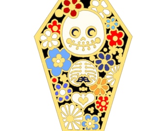 May include: A gold-colored coffin-shaped pin with a black background and a white skeleton face with black eyes and a stitched mouth. The pin is decorated with colorful flowers in shades of red, blue, yellow, and white.