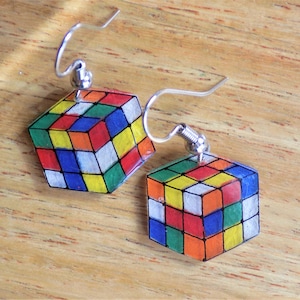 May include: A pair of silver dangle earrings with a colorful Rubik's Cube design. The cubes are made of clear resin with painted details.