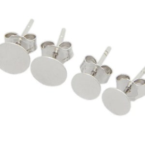May include: Four pairs of silver-colored, round stud earrings. Each earring has a post for insertion into the ear and a flat, circular disc. The earrings are displayed against a white background.