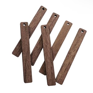 May include: A collection of seven rectangular wooden tags with a wood grain texture. Each tag is a medium brown color and has a small hole drilled at the top. The tags are arranged at various angles against a white background.