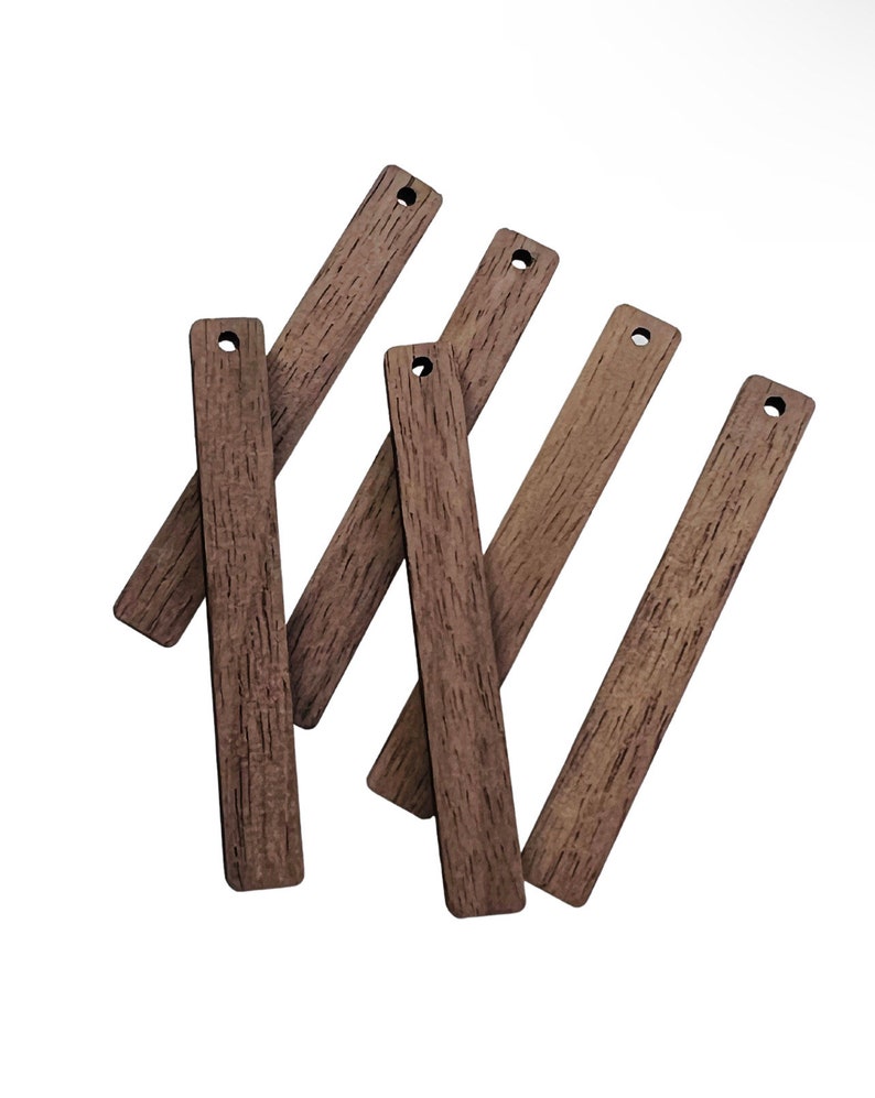 May include: A collection of seven rectangular wooden tags with a wood grain texture. Each tag is a medium brown color and has a small hole drilled at the top. The tags are arranged at various angles against a white background.