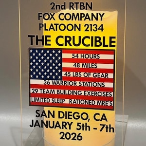 May include: Clear acrylic display with text: "JOHN SMITH JR. 2nd RTBN FOX COMPANY PLATOON 2134 THE CRUCIBLE." Includes an American flag graphic with details: 54 HOURS, 48 MILES, 45 LBS OF GEAR.  Event details: SAN DIEGO, CA, JANUARY 5th - 7th, 2026.