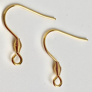 K&ouml;nnte beinhalten: Zwei goldfarbene Ohrringhaken. Jeder Haken hat ein gebogenes Design mit einem gewickelten Drahtdetail in der N&auml;he des Bodens und einer kleinen Schlaufe. Die Haken sind f&uuml;r die Schmuckherstellung und das Basteln konzipiert.