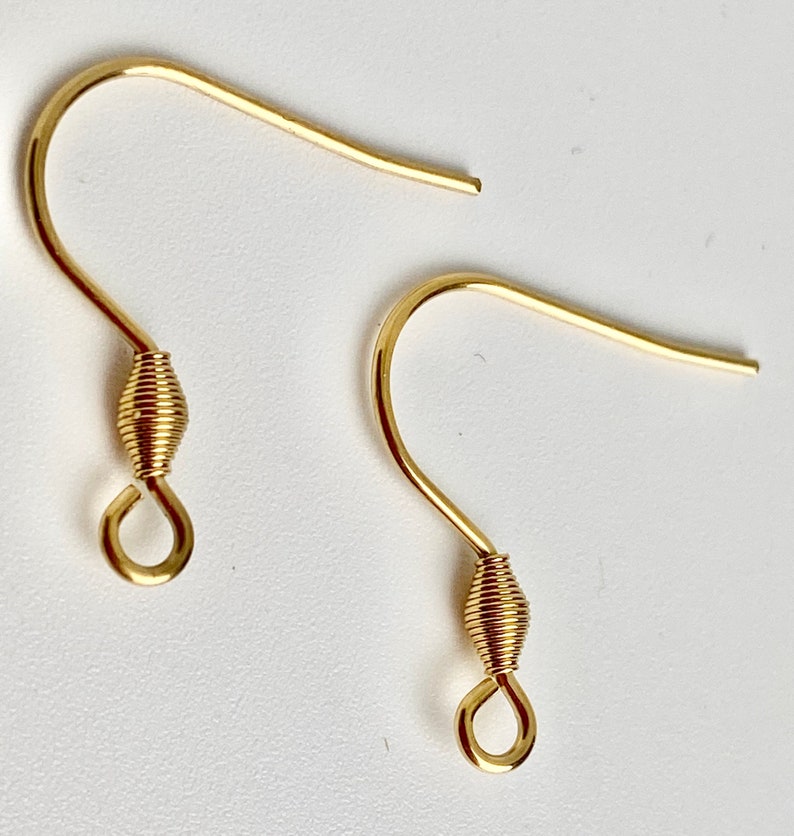 K&ouml;nnte beinhalten: Zwei goldfarbene Ohrringhaken. Jeder Haken hat ein gebogenes Design mit einem gewickelten Drahtdetail in der N&auml;he des Bodens und einer kleinen Schlaufe. Die Haken sind f&uuml;r die Schmuckherstellung und das Basteln konzipiert.
