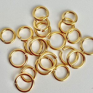 K&ouml;nnte beinhalten: Eine Ansammlung kleiner, goldfarbener Binderinge, teils offen, teils geschlossen, auf wei&szlig;em Untergrund. Die kreisf&ouml;rmigen Ringe sind vermutlich aus Metall und werden f&uuml;r Schmuckherstellung oder Bastelarbeiten verwendet.