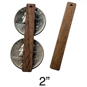 May include: Two rectangular wooden pieces, each with a small hole at the top, are displayed. One is positioned over two quarters, and the other is to the right. The text "2"" is at the bottom, indicating the length of the wooden pieces.