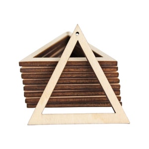 May include: A stack of unfinished wooden triangle shapes. Each triangle has a hole at the top for hanging. The triangles are light brown and appear to be made of thin wood.