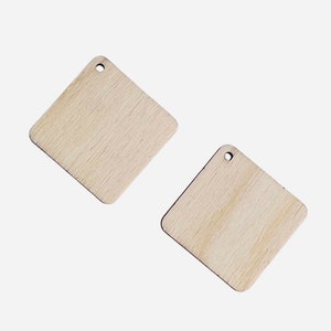 May include: Two diamond-shaped wooden cutouts with a natural wood grain finish. Each cutout has a small hole at the top for hanging. The cutouts are light brown and are set against a white background.