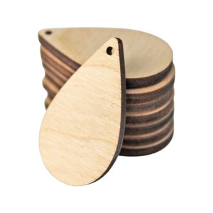 May include: A stack of unfinished wooden teardrop-shaped cutouts with a small hole at the top for crafting. The teardrops are light brown with darker brown edges, and one is positioned in front of the stack.