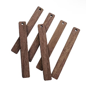 May include: A collection of seven rectangular wooden tags with a dark brown wood grain pattern. Each tag has a small hole drilled at the top. The tags are scattered across a white background.