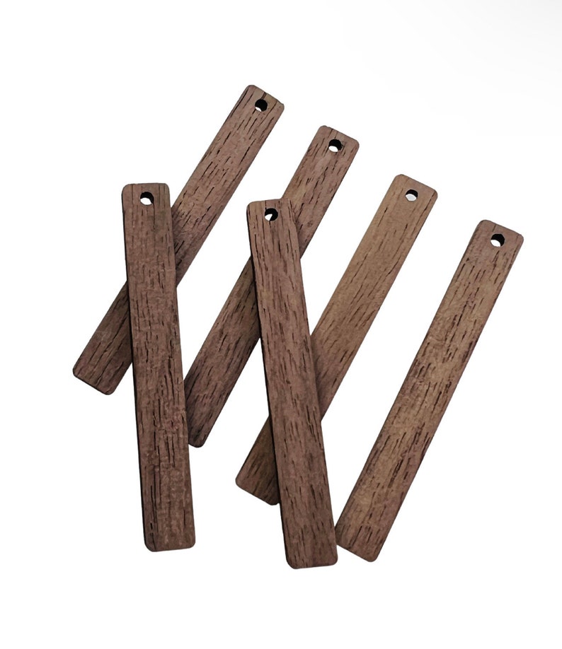 May include: A collection of seven rectangular wooden tags with a dark brown wood grain pattern. Each tag has a small hole drilled at the top. The tags are scattered across a white background.