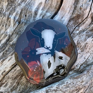 Könnte beinhalten: Eine Schwarzweißillustration einer Ziege mit Totenkopf und Knochen. Die Ziege trägt ein weißes Hemd und hat ein Stück Papier im Maul, auf dem "Property of K.M." steht.