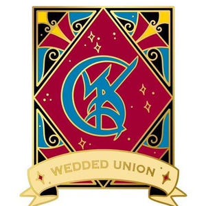 Puede incluir: Pin de esmalte dorado con un diseño rojo, azul y dorado. El pin presenta una luna creciente estilizada con un rayo dentro. El texto "WEDDED UNION" está en una pancarta debajo del diseño.