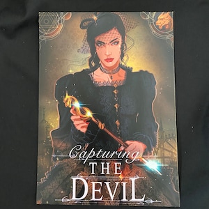 May include: A book cover featuring a woman in a black dress and veil holding a golden staff. The text on the cover reads "Capturing the Devil."