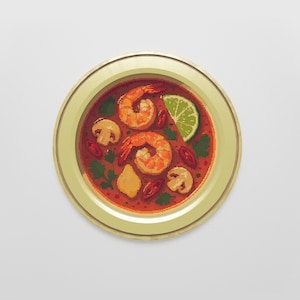 Könnte beinhalten: Ein Kreuzstich-Kunstwerk einer Suppenschüssel mit Garnelen, Pilzen und einer Limettenspalte. Die Suppe hat eine leuchtend rote Farbe, und die Schüssel hat einen goldfarbenen Rand. Das Kunstwerk ist rund und vor einem weißen Hintergrund.