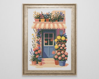 Peut inclure: Impression pixelisée encadrée d'une boutique de fleurs. La boutique présente une porte bleue, un auvent à rayures et est ornée de fleurs en pot de différentes couleurs. L'œuvre d'art est encadrée d'or, créant une scène charmante et accueillante.